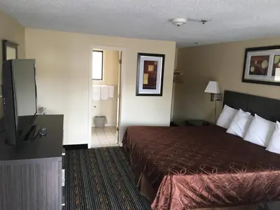 a hotel room with a bed and a bathroom at Whitney Inn & Suites in Hamden