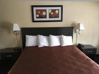 a hotel room with a bed with two nightstands and two lamps at Whitney Inn & Suites in Hamden