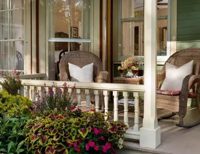 a porch with wicker chairs and flowers on it at Landmark Inn in Cooperstown