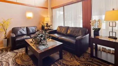 a living room with leather couches and a coffee table at Best Western Clifton Park in Clifton Park