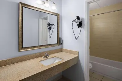 a bathroom with a sink and a mirror at Days Inn by Wyndham Queensbury/Lake George in Queensbury