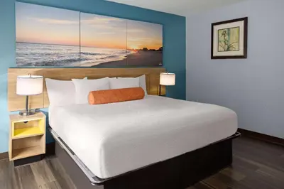a bedroom with a large bed with a large painting on the wall at Days Inn by Wyndham Queensbury/Lake George in Queensbury