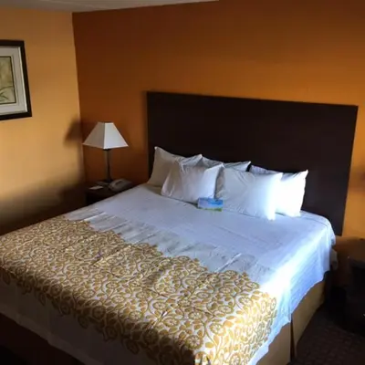 a bedroom with a large bed with white sheets and pillows at Days Inn by Wyndham Queensbury/Lake George in Queensbury