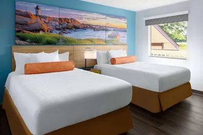 two beds in a room with a painting on the wall at Days Inn by Wyndham Queensbury/Lake George in Queensbury