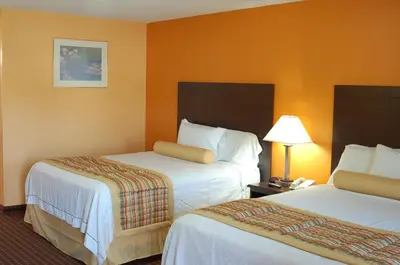 a hotel room with two beds and a lamp at BLUE SKY INN Glens Falls-Saratoga-Lake George in Glens Falls