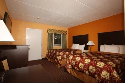 two beds in a hotel room with orange walls at BLUE SKY INN Glens Falls-Saratoga-Lake George in Glens Falls