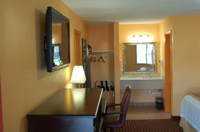 a room with a desk and a bed and a mirror at BLUE SKY INN Glens Falls-Saratoga-Lake George in Glens Falls