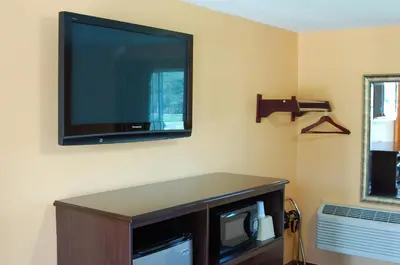 a flat screen tv hanging on a wall at BLUE SKY INN Glens Falls-Saratoga-Lake George in Glens Falls