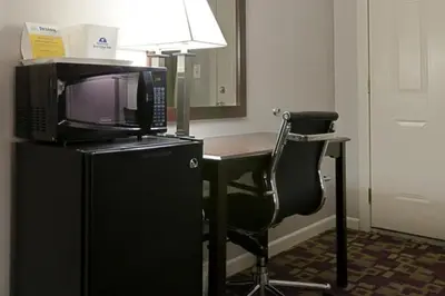 a room with a desk with a microwave and a chair at Mount Holyoke Inn in Holyoke