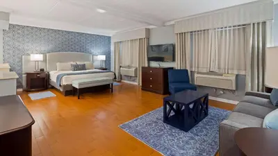a hotel room with a bed and a couch at Best Western PLUS Franklin Square Inn in Troy