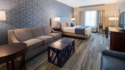 a hotel room with a couch and a bed at Best Western PLUS Franklin Square Inn in Troy
