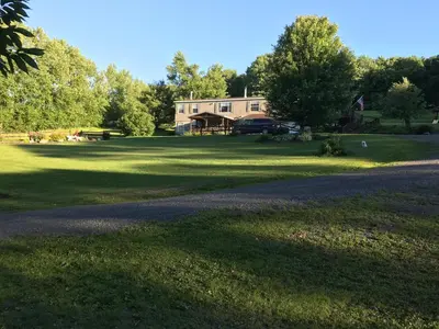 a house on a grass field with a driveway at Coolis Apartment in Richfield Springs