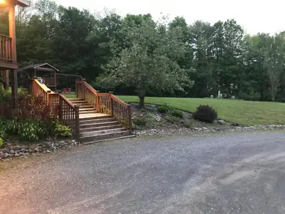 a wooden staircase leading to a house with a lawn at Coolis Apartment in Richfield Springs