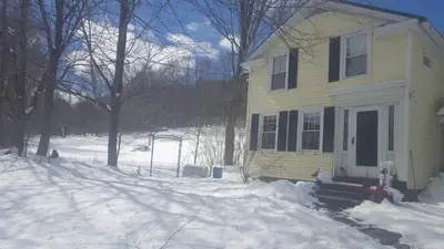 a yellow house with snow in front of it at A Meadow House in Lakeville