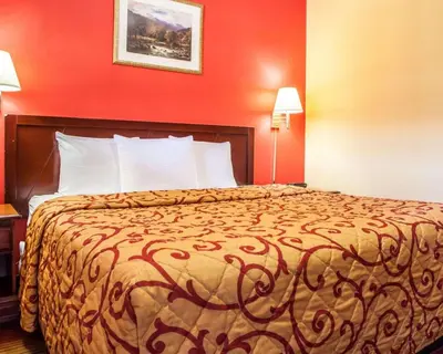a bed in a hotel room with a red wall at Rodeway Inn Jersey City North in Jersey City