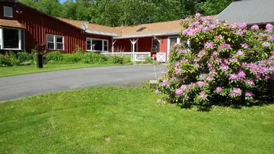 a red building with a bush of flowers in front of it at Cavalier Cottage B&B in Shelburne Falls