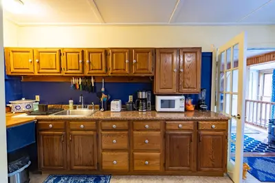 a kitchen with wooden cabinets and a sink at Cavalier Cottage B&B in Shelburne Falls
