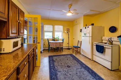 a kitchen with a white refrigerator and a table at Cavalier Cottage B&B in Shelburne Falls