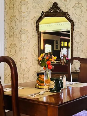 a table with a vase of flowers and a mirror at Manor House Inn in Norfolk