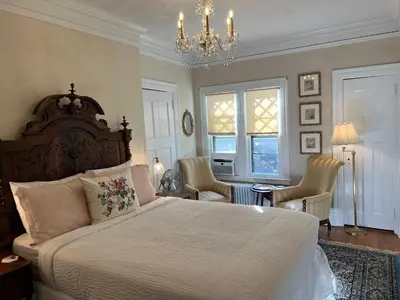 a bedroom with a large bed and chairs and a chandelier at Manor House Inn in Norfolk