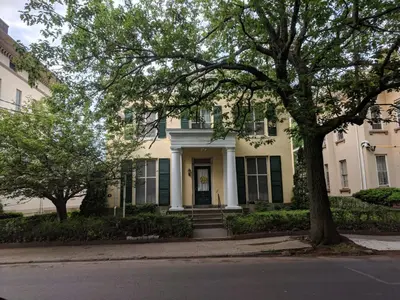 a white house with green shutters and a tree at The Historic Mansion in New Haven