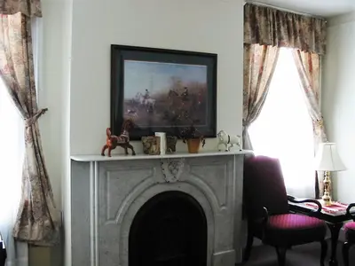 a living room with a fireplace with a painting above it at The Historic Mansion in New Haven