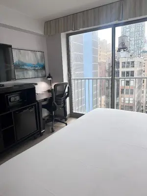 a bedroom with a bed and a desk and a large window at Fairfield Inn & Suites by Marriott New York Manhattan/Chelsea in New York