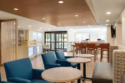 a lobby with tables and chairs and a kitchen at Holiday Inn Express Hartford South - Rocky Hill by IHG in Rocky Hill