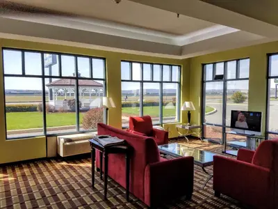 a living room with red chairs and a tv and windows at Days Inn by Wyndham Windsor Locks / Bradley Intl Airport in Windsor Locks