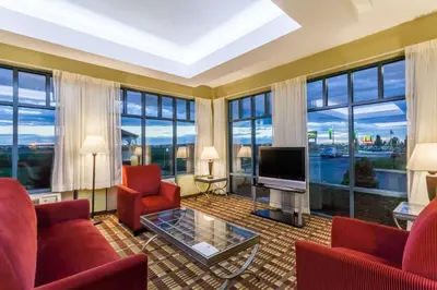 a living room with red furniture and large windows at Days Inn by Wyndham Windsor Locks / Bradley Intl Airport in Windsor Locks
