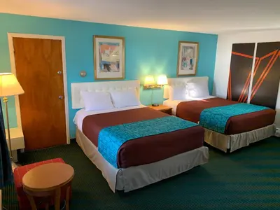 two beds in a hotel room with blue walls at Howard Johnson by Wyndham Williamstown in Williamstown