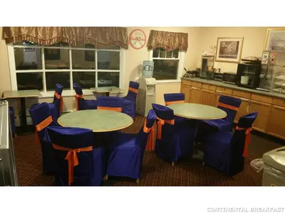 a kitchen with two tables and blue chairs at Howard Johnson by Wyndham Williamstown in Williamstown