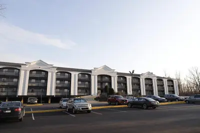 a large building with cars parked in a parking lot at TraveIodge by Wyndham Parsippany in Parsippany