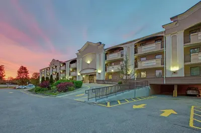 a large apartment building with a parking lot at TraveIodge by Wyndham Parsippany in Parsippany