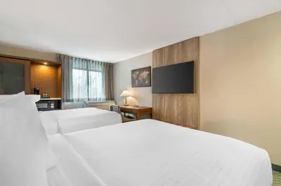 a hotel room with two beds and a flat screen tv at The Clocktower Hotel Latham - North Albany, an Ascend Collection Hotel in Cohoes