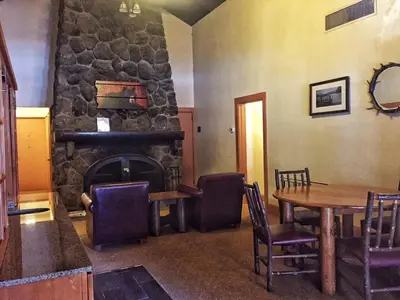 a room with a table and a stone fireplace at Overlook Lodge and Stone Cottages at Bear Mountain in Highland Falls