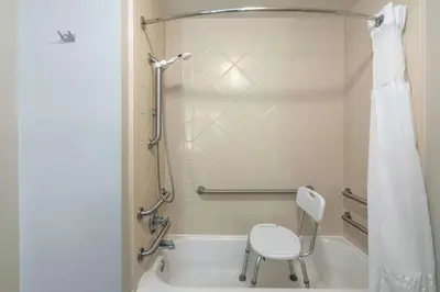 a shower with a white chair in a bathroom at La Quinta by Wyndham Latham Albany Airport in Latham