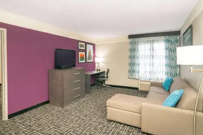 a hotel room with a couch and a tv at La Quinta by Wyndham Latham Albany Airport in Latham
