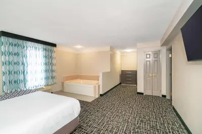 a hotel room with a bed and a tub at La Quinta by Wyndham Latham Albany Airport in Latham