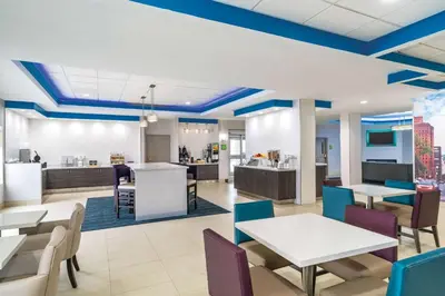 a rendering of a cafeteria with tables and chairs at La Quinta by Wyndham Latham Albany Airport in Latham