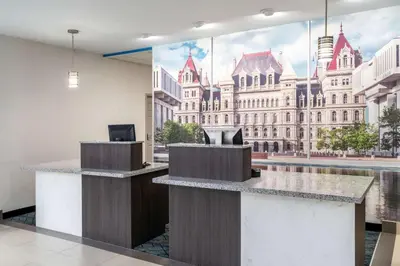 a lobby with a large mural of a building at La Quinta by Wyndham Latham Albany Airport in Latham