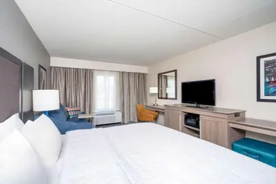 a hotel room with a bed and a flat screen tv at Hampton Inn Clifton Park in Clifton Park