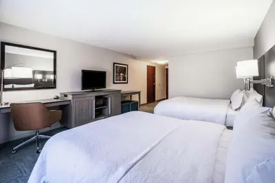 a hotel room with two beds and a desk and a television at Hampton Inn Clifton Park in Clifton Park