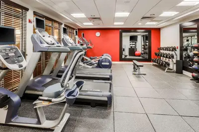 a gym with cardio equipment and red walls at Homewood Suites by Hilton Long Island-Melville in Plainview