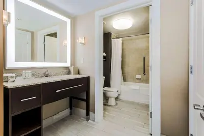 a bathroom with a sink and a toilet and a mirror at Homewood Suites by Hilton Long Island-Melville in Plainview