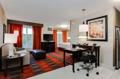 a hotel room with a desk and a bed at Homewood Suites by Hilton Long Island-Melville in Plainview