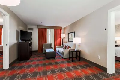 a hotel room with a couch and a bed and a television at Homewood Suites by Hilton Long Island-Melville in Plainview