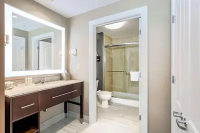 a bathroom with a sink and a toilet and a mirror at Homewood Suites by Hilton Long Island-Melville in Plainview