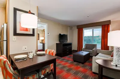 a living room with a table and a living room with a couch at Homewood Suites by Hilton Long Island-Melville in Plainview
