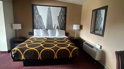 a large bed in a hotel room with a picture on the wall at Super 8 by Wyndham Albany in Albany